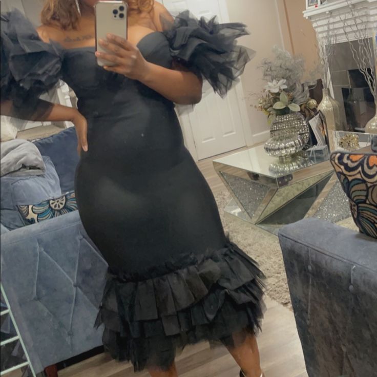 a woman taking a selfie in a mirror wearing a black dress with ruffles