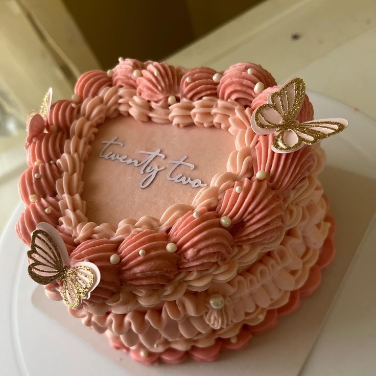 a heart shaped cake decorated with pink icing and butterflies