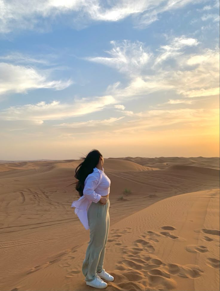 a woman standing on top of a sand dune