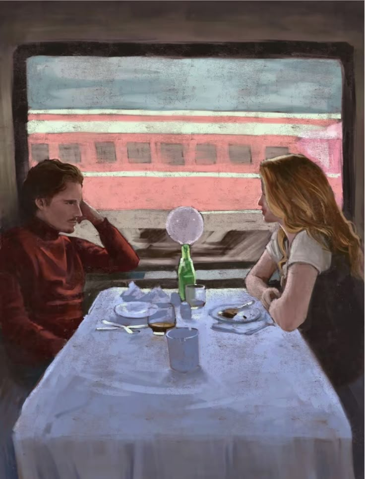 a man and woman sitting at a table in front of a window looking out the train