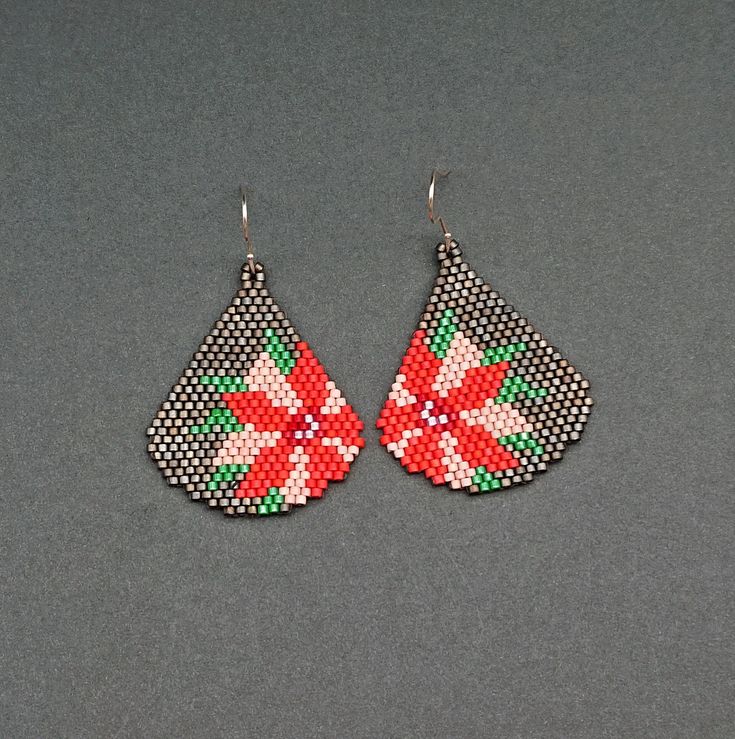 a pair of red and green beaded earrings on a gray surface with white dots