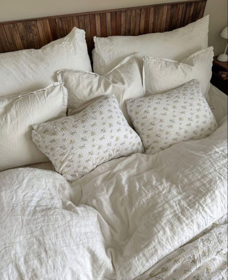 an unmade bed with white linens and pillows