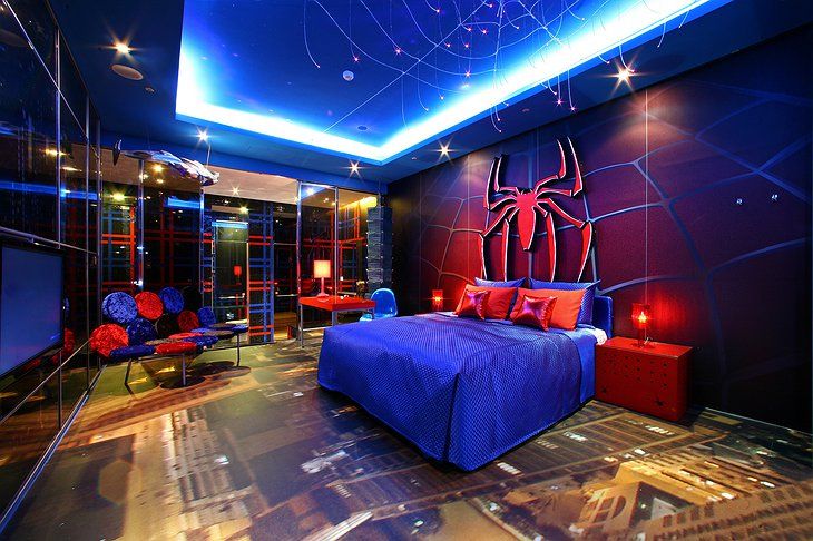 a bed room with a neatly made bed and a spiderman mural on the wall