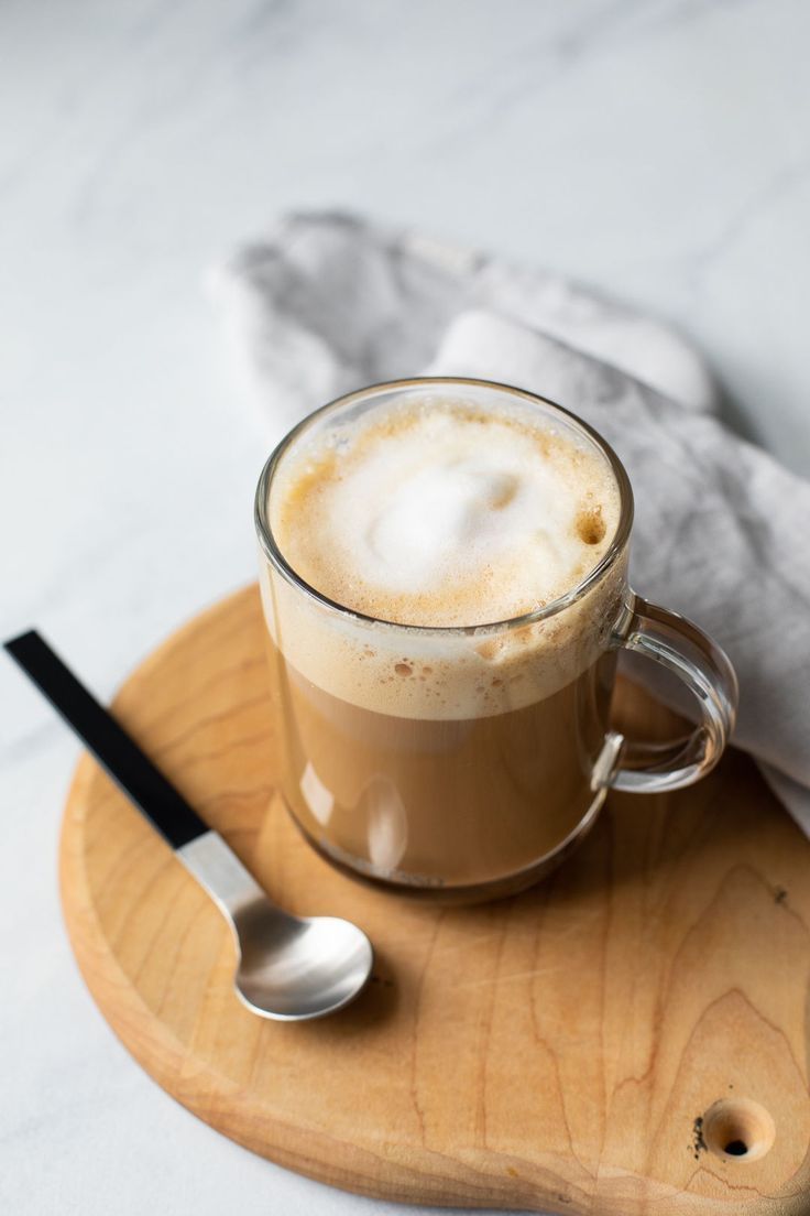 a cup of coffee on a wooden tray with a spoon and napkin next to it