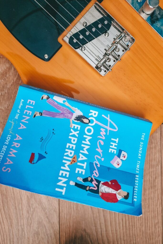 an electric guitar sitting on top of a wooden floor next to a book titled the bohemian entertainment arts