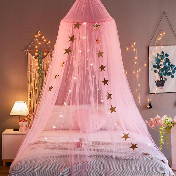 a pink canopy bed with gold stars on it