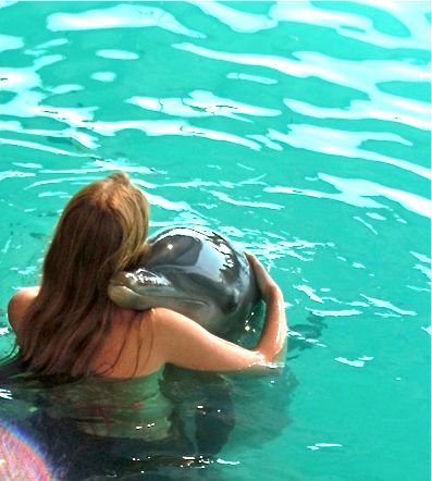 a woman swimming in the water with a dolphin