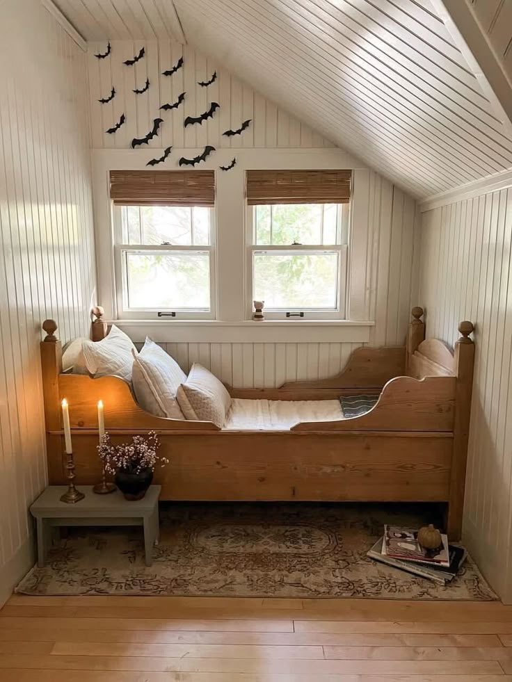 a bedroom with white walls and wooden floors has bats on the wall above the bed