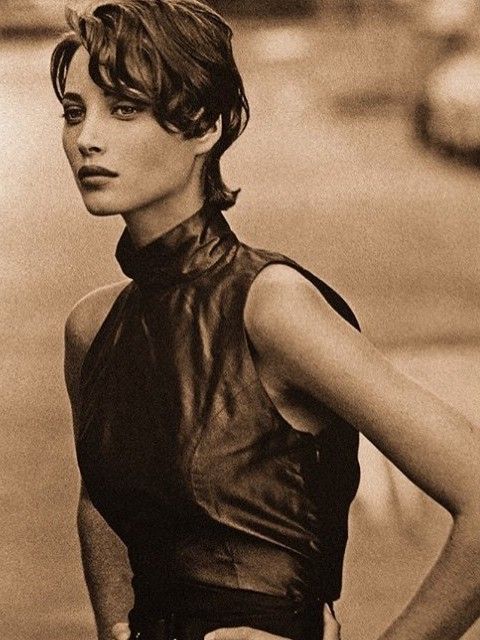 a black and white photo of a woman with her hands on her hips wearing a leather top