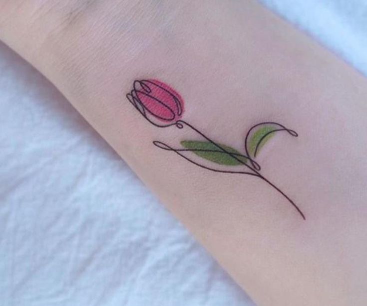 a small pink flower on the wrist with green leaves and petals in it's center