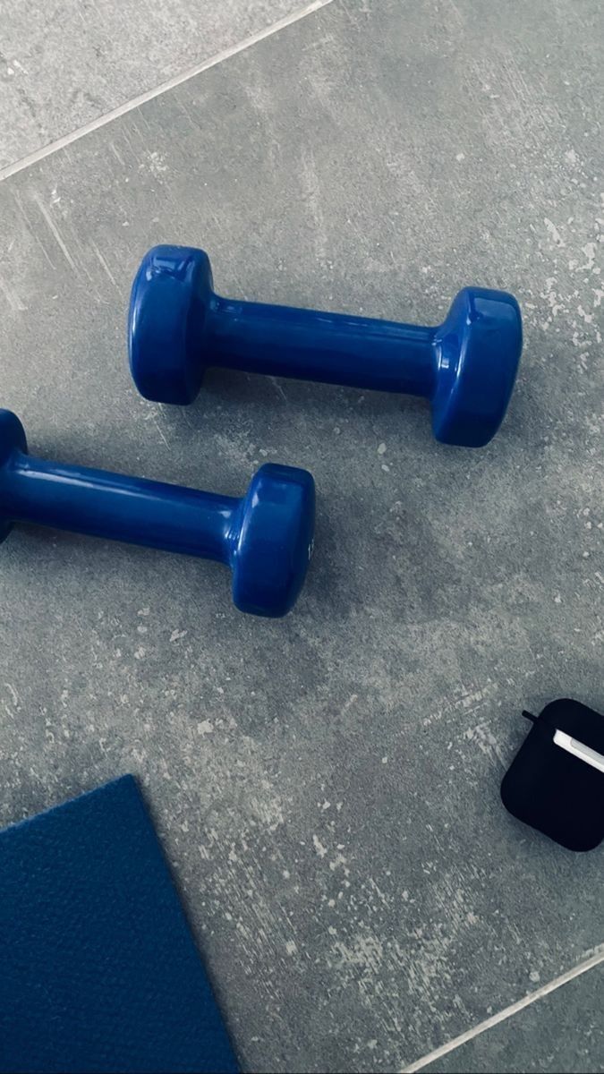 two blue dumbbells sitting on the ground next to a wallet