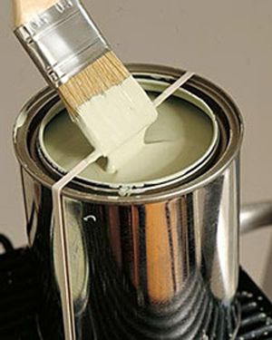 a paintbrush is being used to brush the interior of a metal can on top of a stove