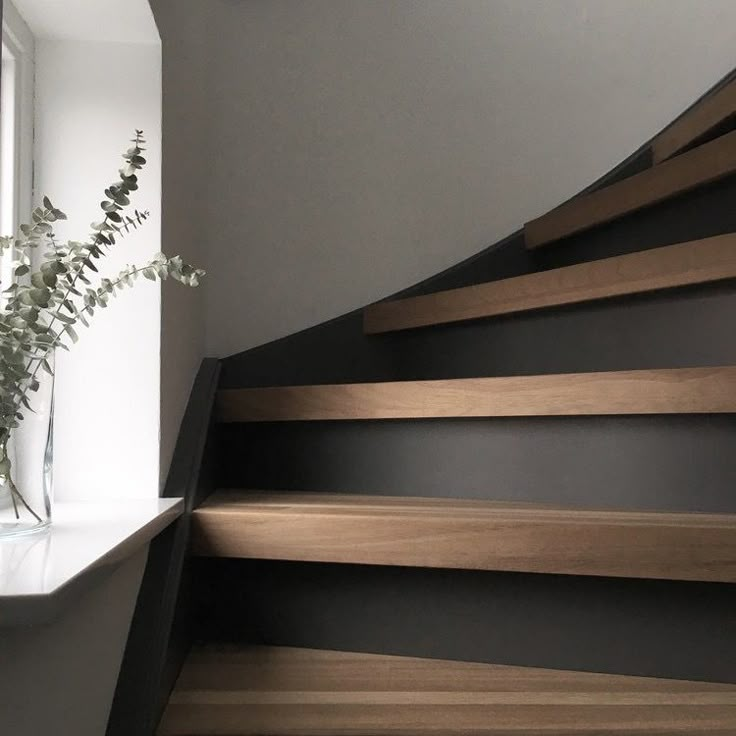 a vase filled with flowers sitting on top of a set of stairs next to a window