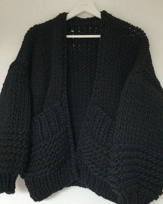 a black cardigan sweater hanging on a white hanger, with the top half open