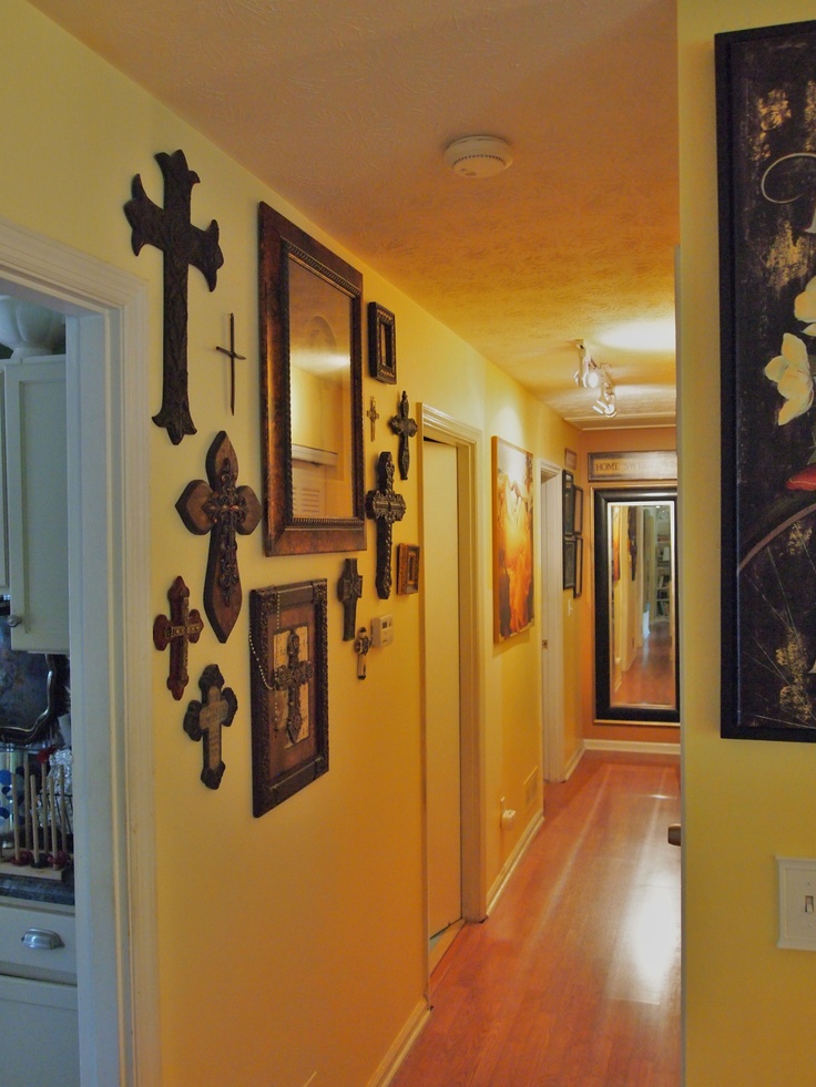 a long hallway with crosses on the wall and pictures hanging on the wall above it