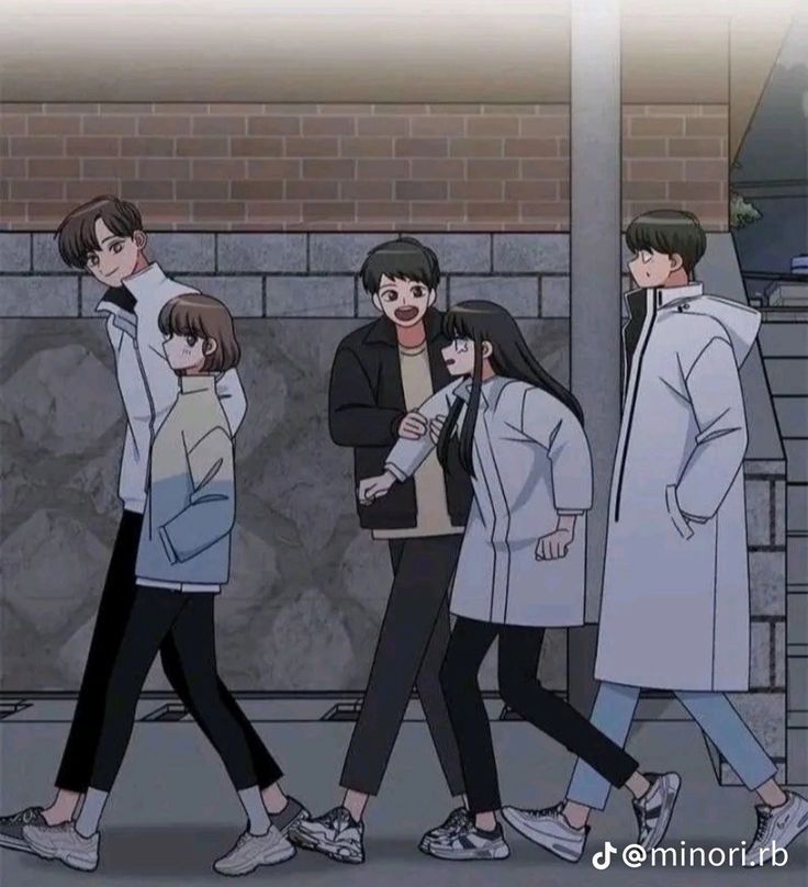 people are walking down the street in front of a brick wall, with one person wearing a white coat