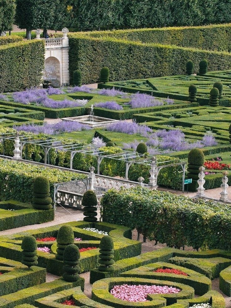 an elaborate garden with hedges and flowers in the center