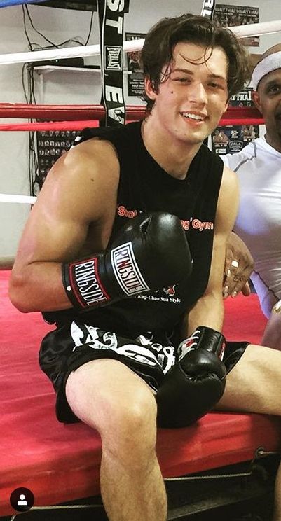 a man sitting on top of a red bench next to another man wearing boxing gloves