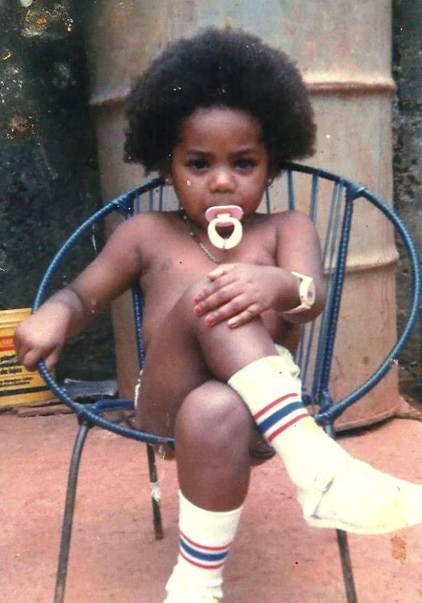 a young child sitting in a chair with a pacifier in her mouth and wearing socks