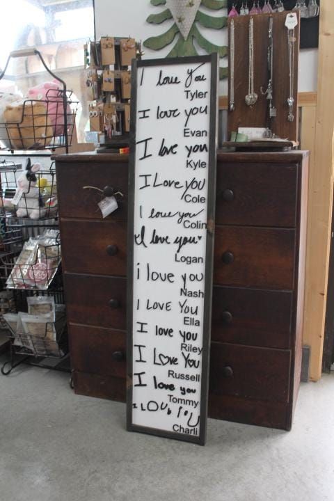 a wooden sign with writing on it sitting in front of a dresser and other items