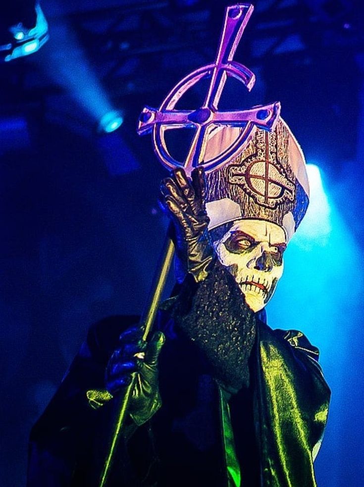 a masked man with a cross on his head holding a stick in front of him