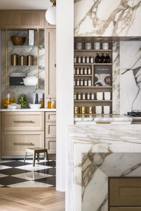 a kitchen with marble counter tops and shelves filled with bottles on top of checkered flooring