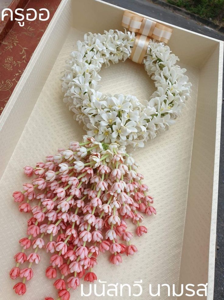 an open box with pink and white flowers on the inside, along with a ribbon tied around it