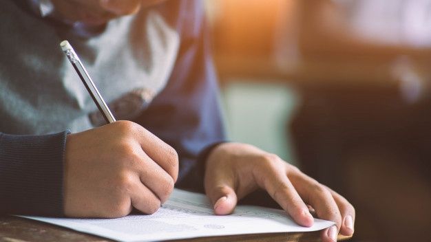 a person writing on a piece of paper with a pen