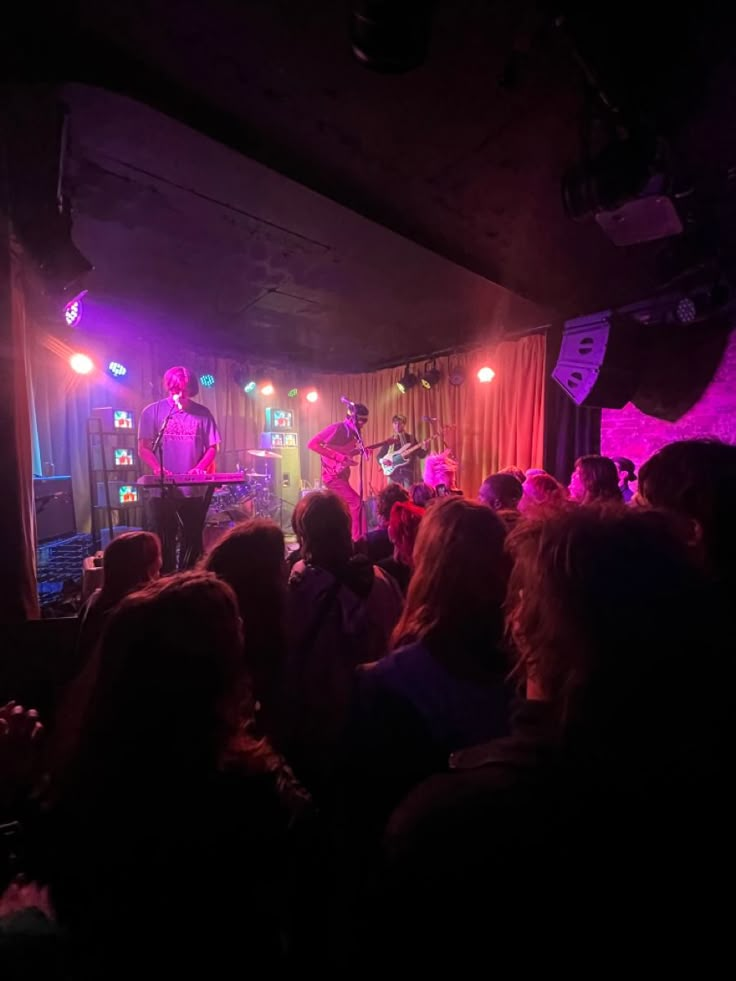 a group of people that are standing in front of a stage with lights on it