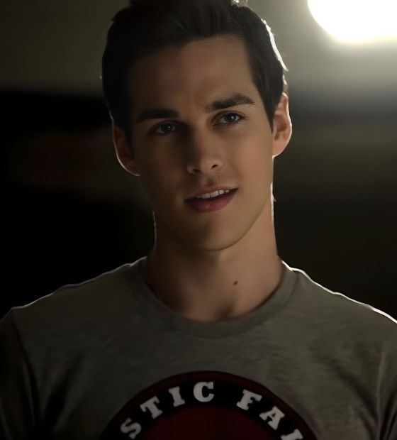 a young man in a gray shirt is looking at the camera with light shining on him