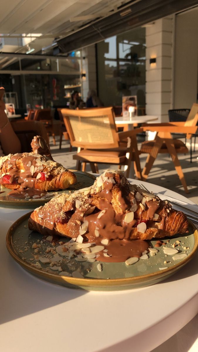 two plates with food on them sitting on a table in front of chairs and tables