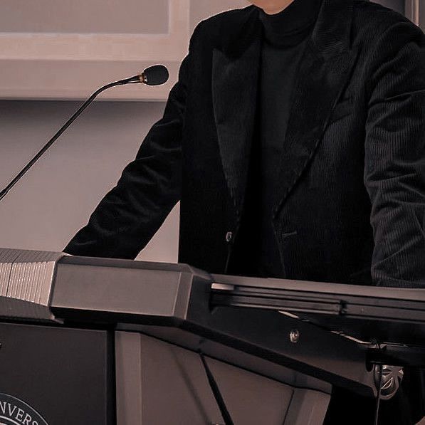 a man standing at a podium in front of a microphone with his hand on top of the podium