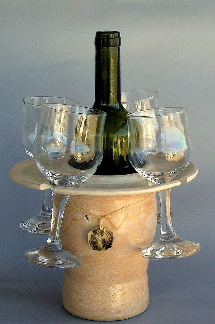 there is a wine bottle and glasses on the top of a stand that has four empty wine glasses in it