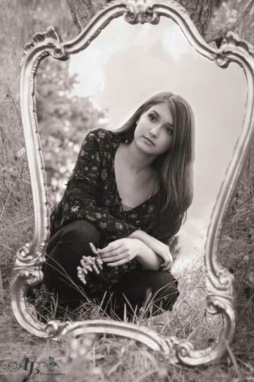 a woman sitting on the ground in front of a mirror