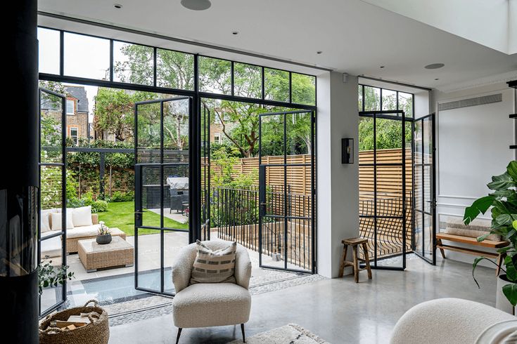 a living room filled with furniture and lots of glass doors leading to an outdoor area