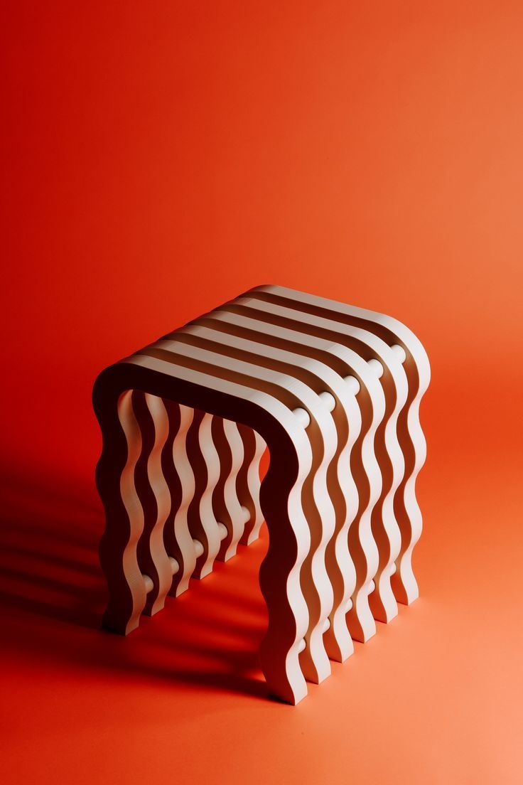 three wooden stools sitting on top of an orange surface in front of a red wall