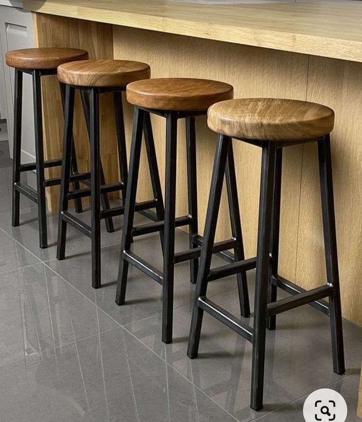 three wooden stools sitting in front of a counter