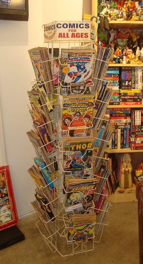 a book stand with comic books on it in front of a wall full of comics