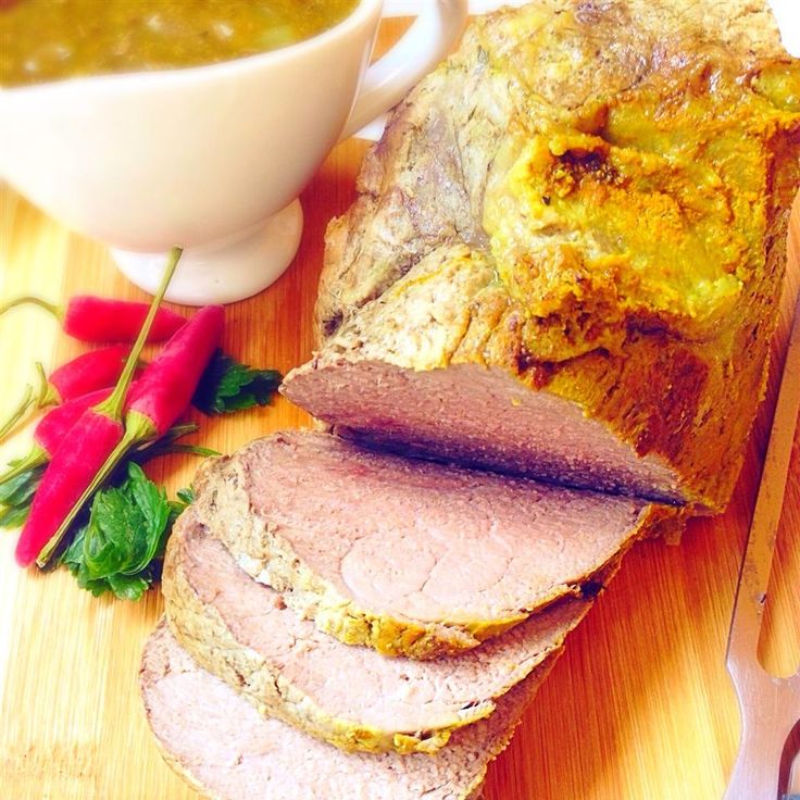 a loaf of meat sitting on top of a cutting board next to a bowl of soup