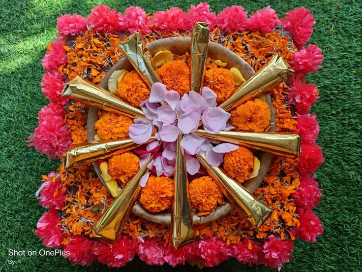 an arrangement of flowers and gold utensils arranged in a circle on the grass