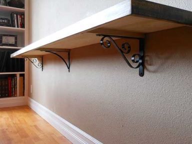 a shelf with two brackets on it in front of a bookcase filled with books