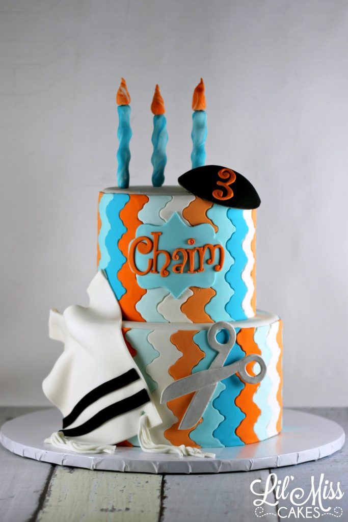 a birthday cake with candles and scissors on the top is decorated in blue, orange and white