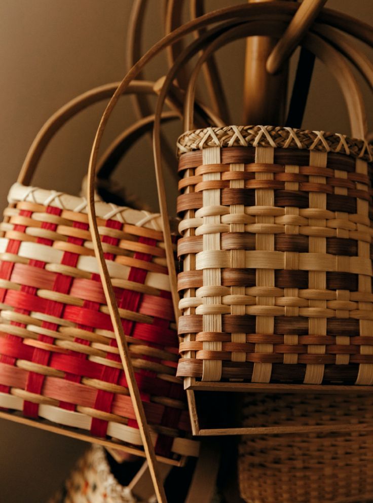 two woven baskets sitting on top of a wooden table next to a lamp shade fixture