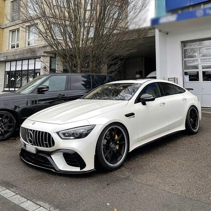 two white mercedess parked in front of a car dealership with their doors open