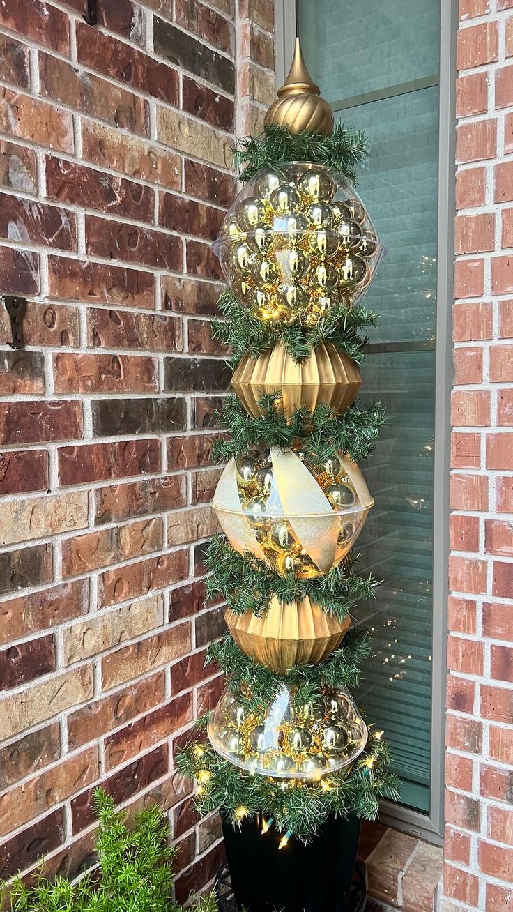 a christmas tree made out of gold and silver ornaments in front of a brick building