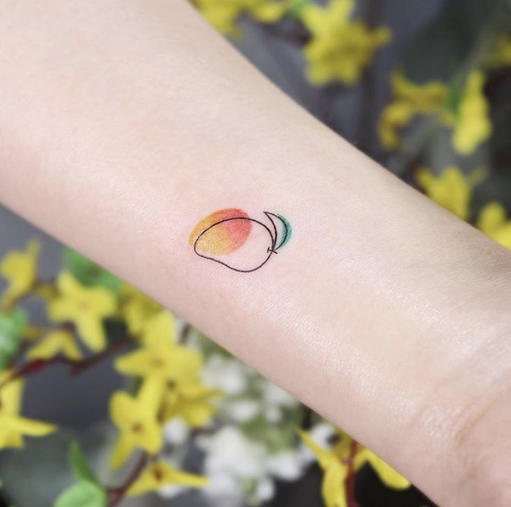 a small peach tattoo on the left inner arm, with green and yellow flowers in the background