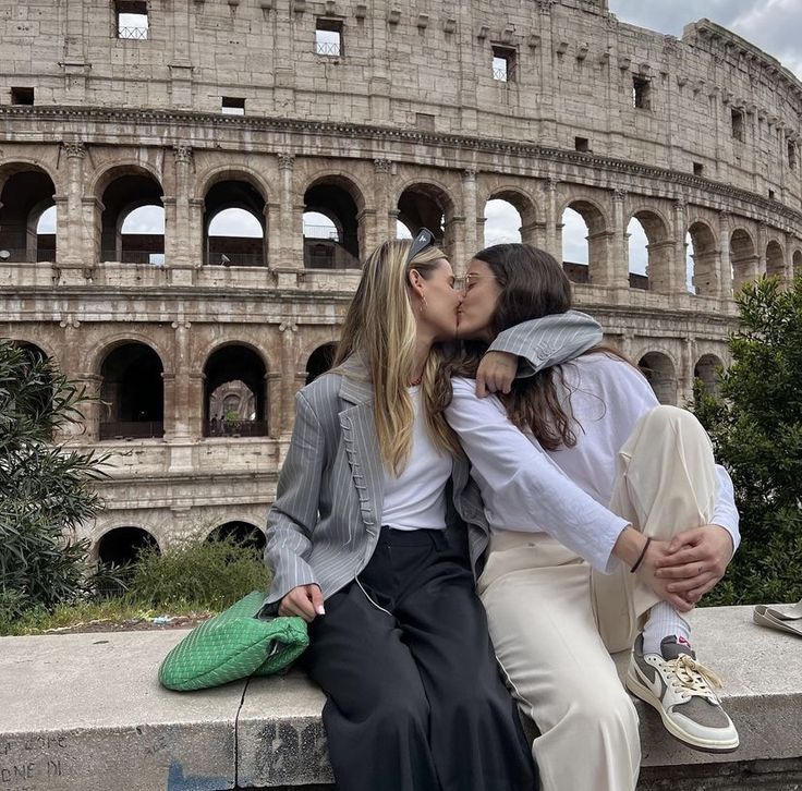 two women kissing each other in front of the colossion