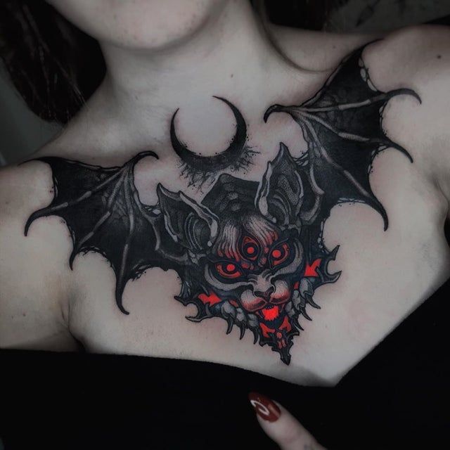 a woman with a bat tattoo on her chest and red glowing eyes in the dark