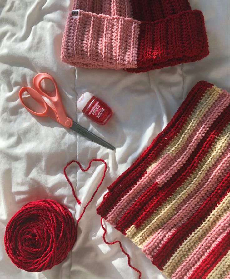 two knitted hats, one with yarn and the other with crochet needles