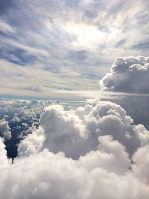 the view from an airplane looking down on clouds and blue sky with white puffy clouds